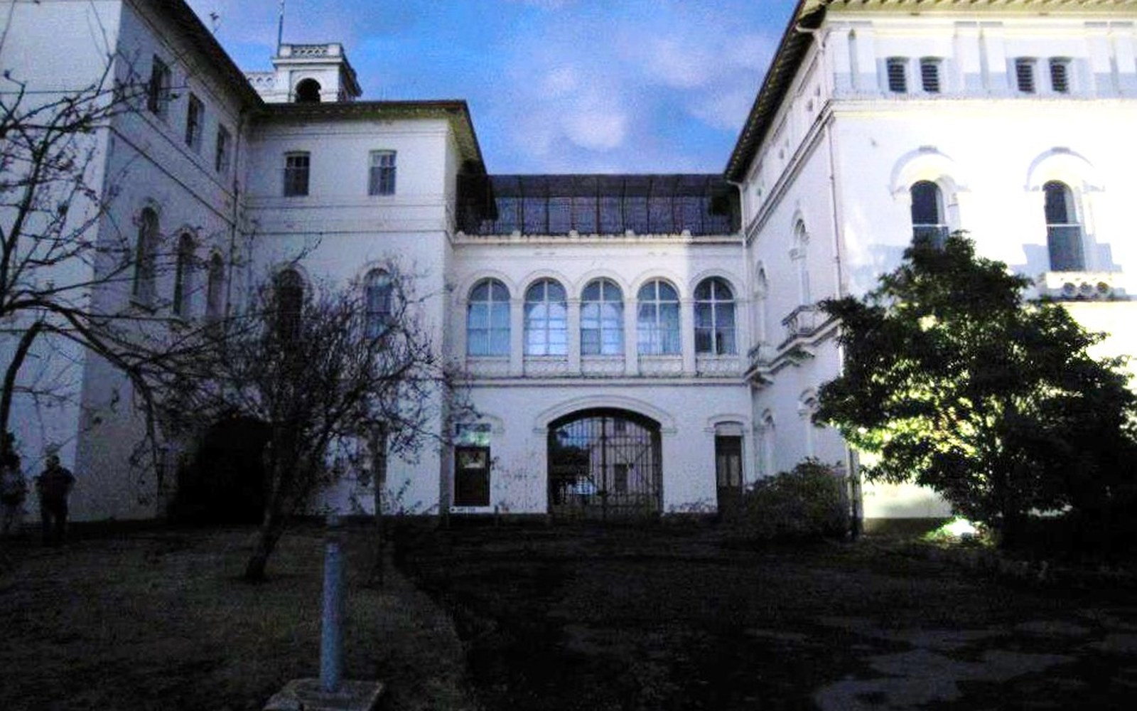Courtyard of an old white building with arched windows lit at dusk