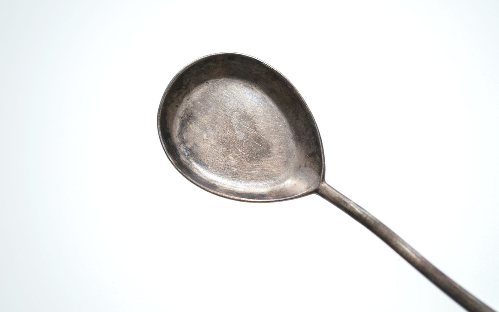 Close-up of a tarnished silver spoon's bowl and part of its curved handle