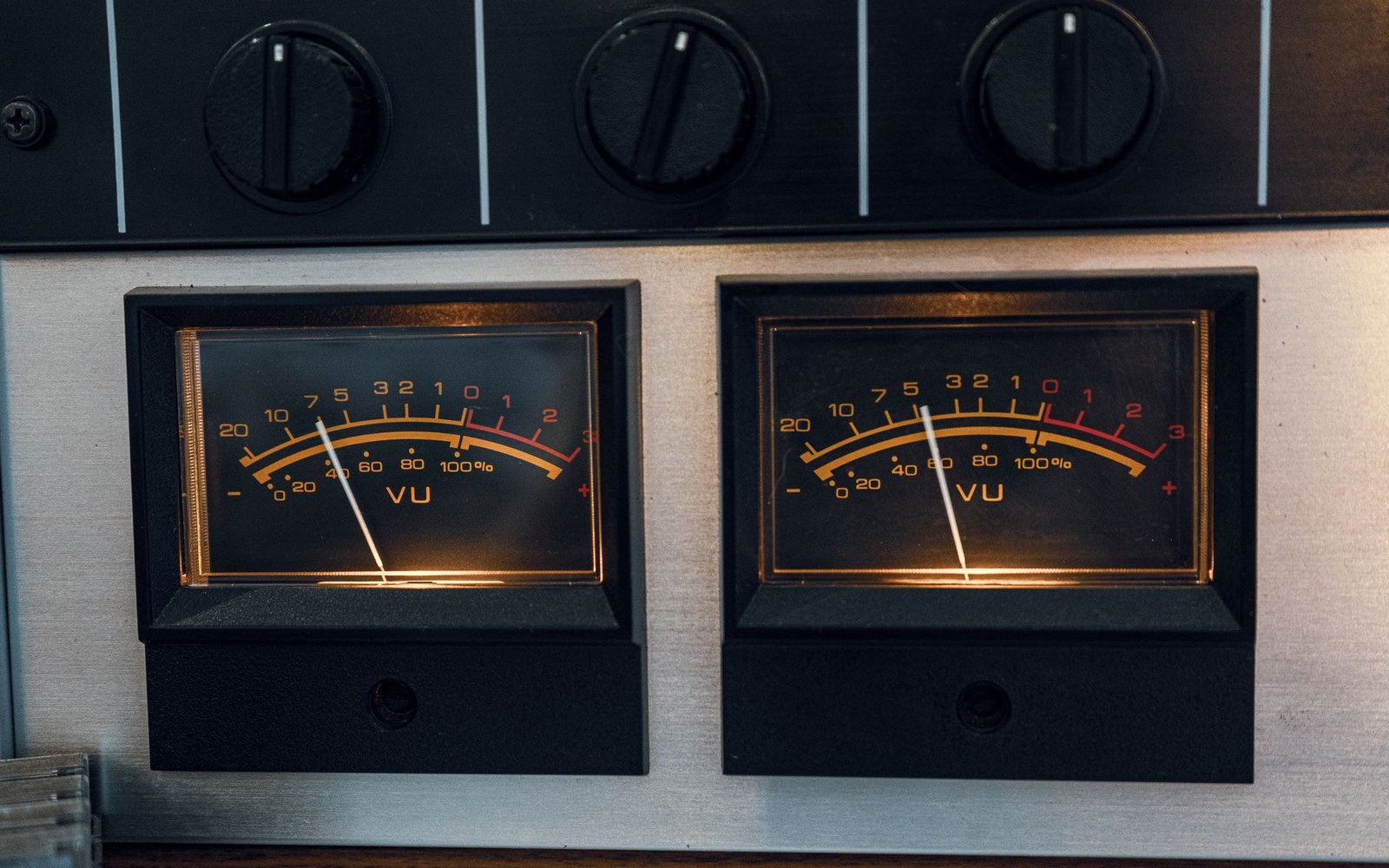 Two illuminated VU meters with needles below zero, mounted beneath control knobs