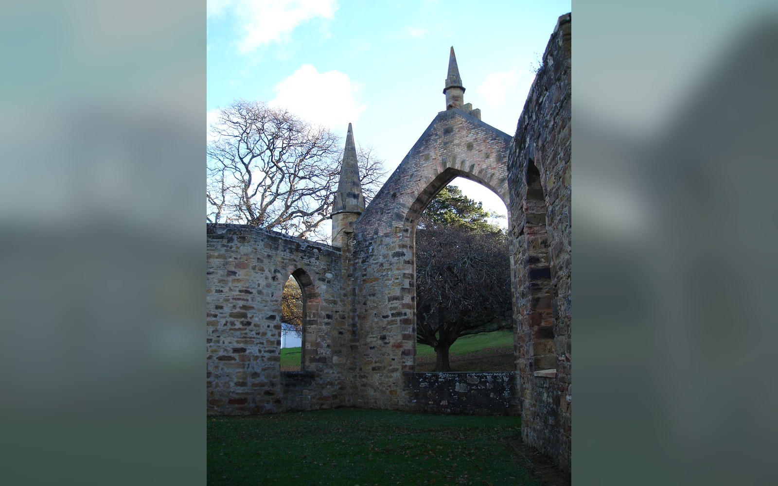 Stone archways with pointed spires stand roofless amid ruins of the old church